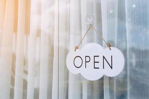 A business sign that says Open on cafe or restaurant hang on door at entrance. photo