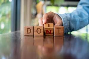 A woman turns a wooden cube with the words do it or don't as a metaphor for making a decision. photo