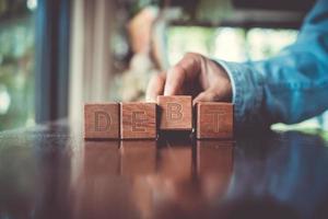 A group wooden cubes on table with word Debt on it background. photo