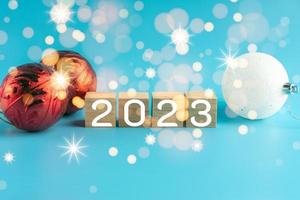 The wooden cube with the word 2022 changes to 2023. New Year Christmas Day. Concept on bokeh and blue background. Close up and copy space on top and under for design or text. photo