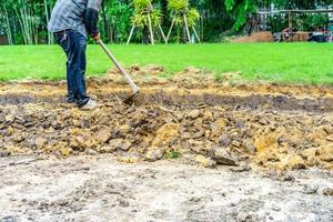 el jardinero cava el suelo con su equipo para jardinería y prepara la tierra para la plantación. foto