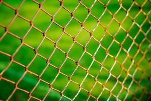 Rust steel net with blur football field. photo