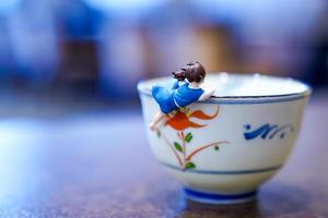 little high school in uniform hang on to rim of tea cup photo