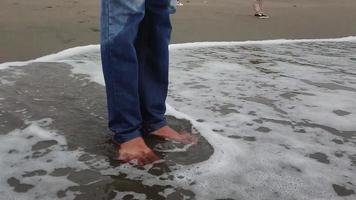 les pieds d'un homme baignés par les vagues de la plage video