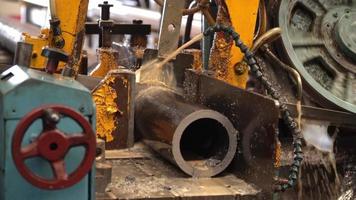 Industrial band saw, cutting metal pipe, coolant in yellow scene, industrial tools video