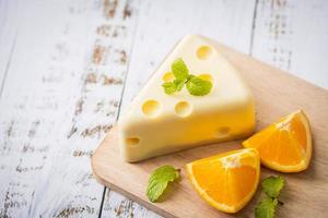 Homemade of Fresh white chocolate cake in a slice of cheese shape putt on white wooden table and mint, orange. Sweet Food and Dessert concept. Sweets decorated for holiday. Close-up dessert view. photo