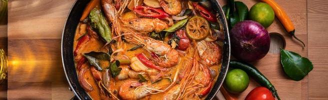 Tom Yum Goong or Tom Yum Kung, Thai hot and sour shrimp soup in pan. Popular Thai food in Thai cuisine restaurant. Shrimp and Spices with lemongrass, lemon, galangal, chili in coconut milk. Banner photo