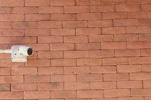 Surveillance cameras are a modern technology to prevent thieves and thieves that are installed on red brick construction as a wall to prevent thieves as well. photo