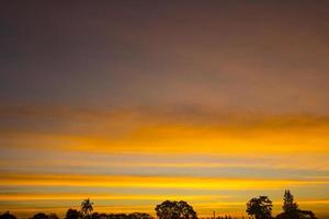 The sky is a horizontal line of yellow-orange and colorful colors in the beautiful evening in the midst of nature which is peaceful, warm and romantic in the countryside and is extremely beautiful. photo