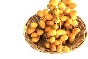 los dátiles amarillos maduros se cultivan orgánicamente, son dulces y deliciosos, y frescos en cestas tejidas, sobre un fondo blanco. foto