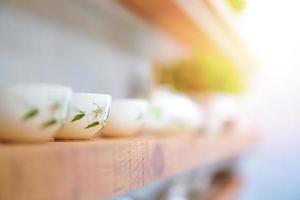 Lilly flower pattern on luxury cup of tea are arranged on the wooden shelf in the line with vivid sunlight effect. photo