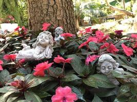 three little cupid angel statue in the green red tree. photo