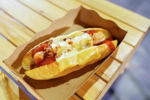 hotdog in the paper plate on the wooden table in foodtruck, food street event, Thailand. photo