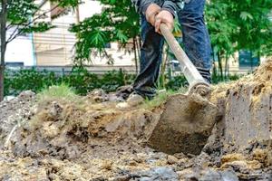 el jardinero cava el suelo con su equipo para jardinería y prepara la tierra para la plantación. foto