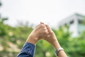 Close up to two Asian females holds hands and raise up to the sky. For showing the team building work and play together. photo