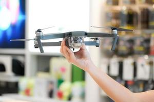 Asian woman hand hold the Gray Drone in blur electronic store. photo