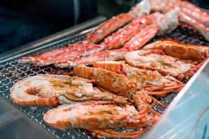 Grilled shrimps and crab on the grill are fire and cooked in fish market, Japan photo