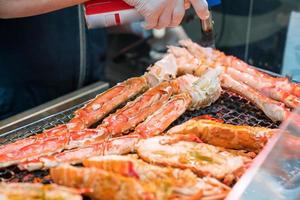 Grilled shrimps and crab on the grill are fire and cooked in fish market, Japan photo