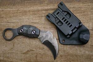 Karambit knife tactical fighter on wood background photo
