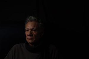 Dark Moody Low Key Portrait of a Mature Man Relaxing in Deep Thought photo