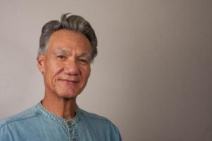 Heads shot Portrait of a mature man 60 plus wearing a Light blue denim shirt photo