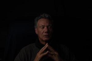 Dark Moody Low Key Portrait of a Mature Man Relaxing in Deep Thought photo