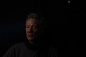 Dark Moody Low Key Portrait of a Mature Man Relaxing in Deep Thought photo