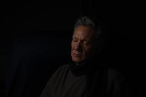 Dark Moody Low Key Portrait of a Mature Man Relaxing in Deep Thought photo