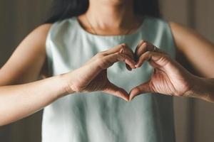 primer plano de una mujer haciendo forma de corazón para el día de san valentín, el día de la madre y el mes de concientización sobre el cáncer de mama para la atención médica del día internacional de la mujer foto