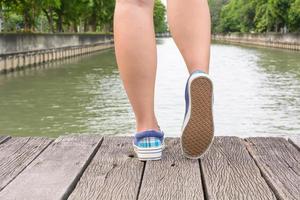 Canvas sneakers on feet on the wooden bridge photo