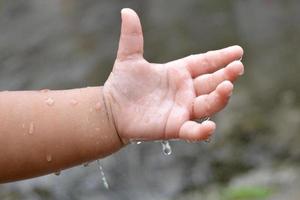 la mano del niño está jugando con gotas de lluvia. foto