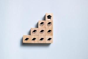 Top view wooden blocks set to step with book icon to graduate icon. Concept for learning and education. photo