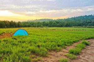 The small tent in the meadow with trees and sky in the background photo