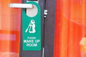 Open door with sign PLEASE MAKE UP ROOM on handle and Orange Curtain at hotel photo