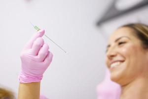 Doctor showing a PDO treatment suture thread to her patient. photo