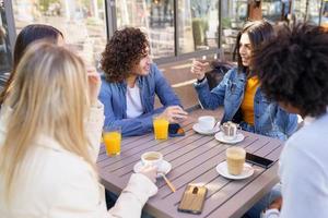 Multi-ethnic group of friends having a drink together in an outdoor bar. photo