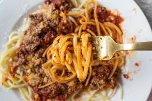 spaghetti with ground beef meat sauce on plate with noodles wrapped around fork photo