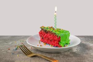 rebanada de pastel casero de color verde brillante y rosa con velas y chispas foto