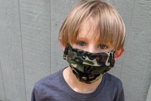 young boy wearing homemade virus protection mask outside photo