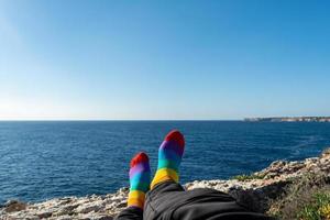 socks with the colors of the flag of the lgtb community. relaxed in front of the sea. Pride concept with copy space photo