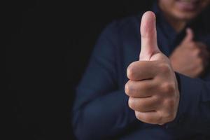 Person that wear dark blue shirt shows thumbs up sign. Salaryman or business man. Like or good concept. Close up shot with copy space. photo