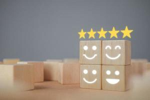 Evaluation and satisfaction concept. Five stars and smile emojis show an excellent job. Close up shot on wood block with copy space. There some noise and gain. photo