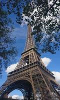 el símbolo más hermoso de parís, la vista de ángulo bajo de la torre eiffel, con árboles y hojas en primer plano foto