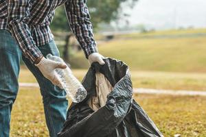 un hombre está recogiendo basura en un parque, no tirando basura en la basura puede arruinar la belleza del área del jardín y también causar el calentamiento global y dañar a los animales. concepto de limpieza en áreas públicas. foto