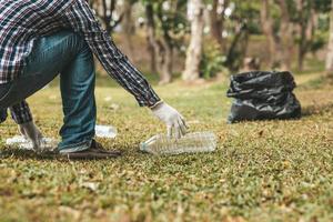 A man is picking up trash in a park, not throwing trash in the trash can ruin the beauty of the garden area and also cause global warming and harm animals. Concept of cleanliness in public areas. photo
