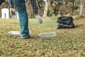 un hombre está recogiendo basura en un parque, no tirando basura en la basura puede arruinar la belleza del área del jardín y también causar el calentamiento global y dañar a los animales. concepto de limpieza en áreas públicas. foto