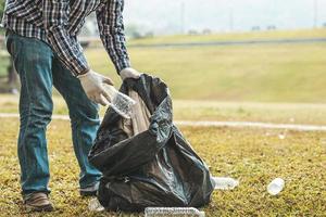 A man is picking up trash in a park, not throwing trash in the trash can ruin the beauty of the garden area and also cause global warming and harm animals. Concept of cleanliness in public areas. photo