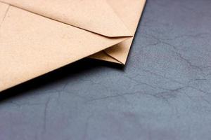 Corners of light brown kraft paper envelopes lying on dark textured background, horizontal photo. Empty space, objects in upper left corner, clean sheet photo