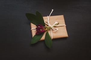 Gift box in craft packaging on wooden black background photo