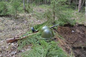 a wartime helmet and a machine gun lie on the edge of the trench photo